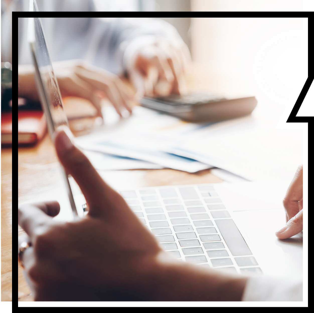 Hände von zwei Personen, Laptop und Unterlagen auf dem Tisch